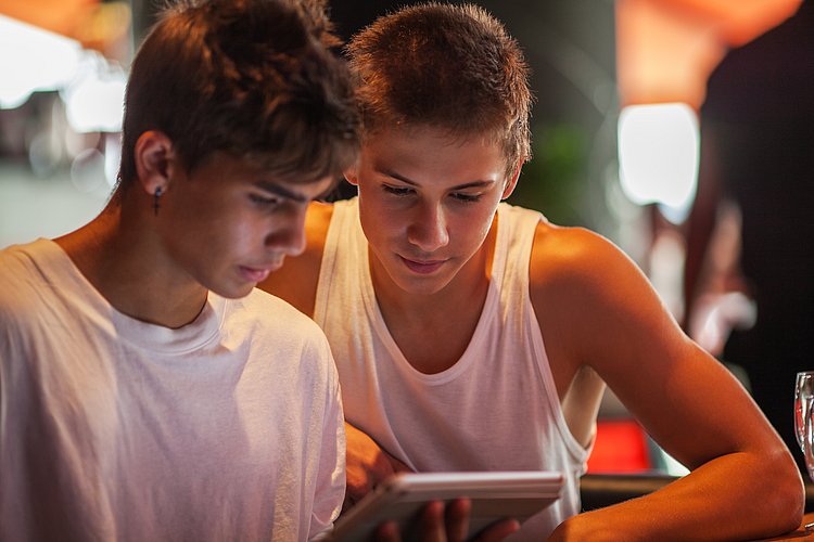 2 Teenager blicken gemeinsam auf ein Tablet